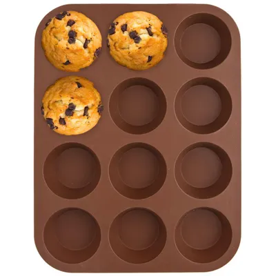 A top-down view of a brown silicone muffin tin with three chocolate chip muffins in the top-left corner.