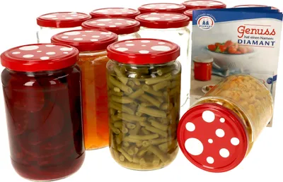 A collection of glass jars filled with preserved food, with a recipe booklet in the background.