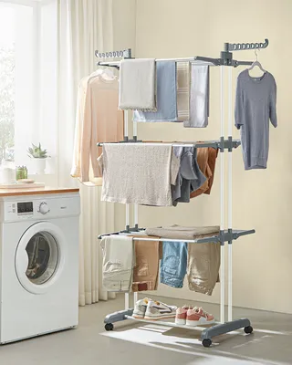A laundry drying rack with clothes and a washing machine in a laundry room.