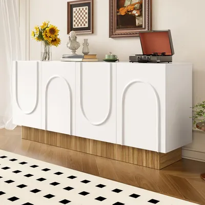 A modern white sideboard with a ribbed wood-tone base is displayed in a well-decorated living room, featuring artwork and decorative items on top.