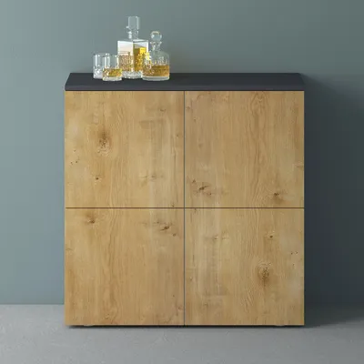 A cabinet with four doors and a dark top, with two glasses and two bottles of liquor on top.