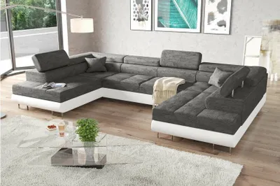 A modern living room with a large sectional sofa, coffee table, and artwork on the wall.