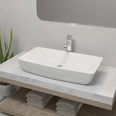 A white rectangular sink with a chrome faucet sits on a marble countertop above wooden shelves with folded towels.