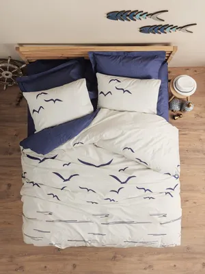 A top-down view of a bed with dark blue and white bedding featuring a seagull print.
