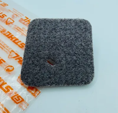 A close-up of a gray air filter with an orange and white branded plastic bag in the background.