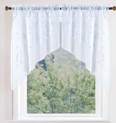 A white lace curtain with a scalloped bottom edge is shown hanging on a window rod, with trees and foliage visible through the window.