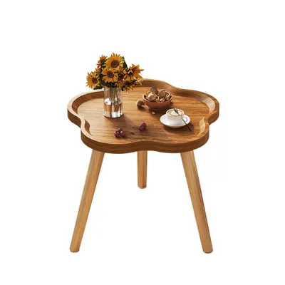 A wooden side table with a vase of sunflowers, a bowl of nuts, and a cup of coffee.