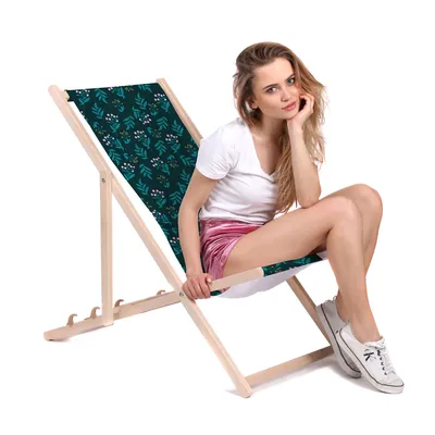 A woman is sitting on a foldable deck chair with a floral pattern.