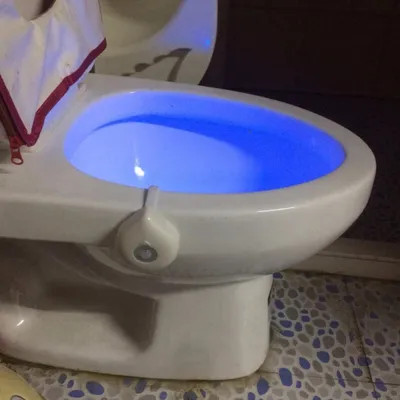 A toilet bowl with a blue LED light illuminating the water.