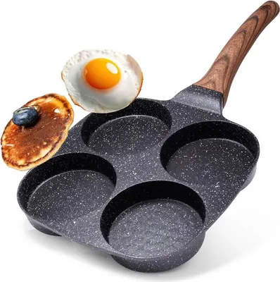 A frying pan with multiple circular molds, designed for cooking eggs or pancakes, is shown with a fried egg and a pancake placed next to it.