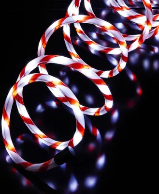 A coiled rope light with red and white stripes against a black background.