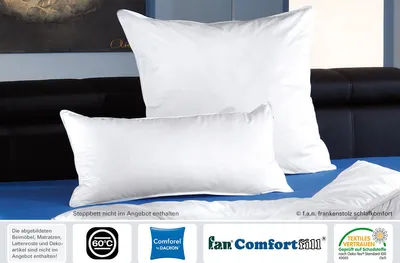Two white pillows are displayed on a blue surface in front of a dark headboard.