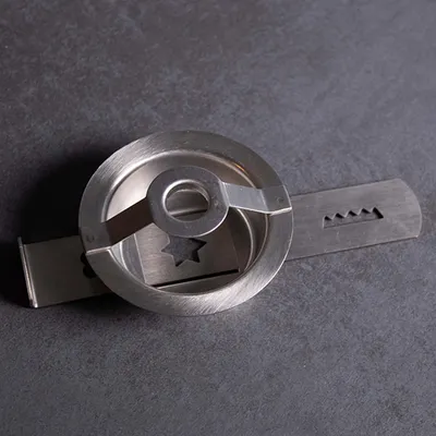 A close-up, angled view of a metal cookie press attachment on a dark gray surface.