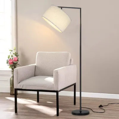 A modern floor lamp is positioned next to a beige armchair in a room.