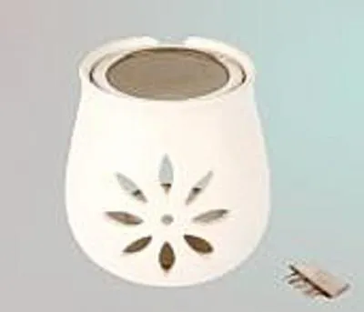 A white ceramic incense burner with a floral cut-out design and a metal sieve on top, placed on a light gray and blue gradient background. A small wooden item is to the right of the burner.