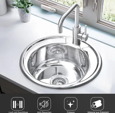A stainless steel kitchen sink with a faucet, set on a white countertop next to a window.