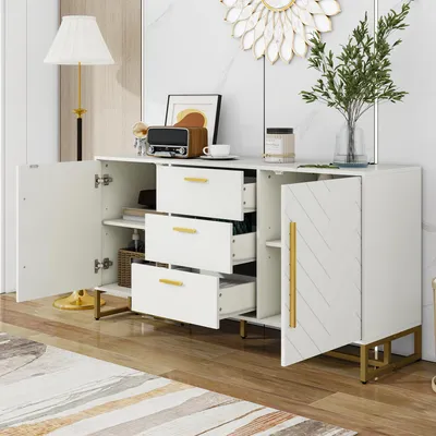 A white sideboard with gold accents, featuring open doors and drawers, displaying decorative items and plants.