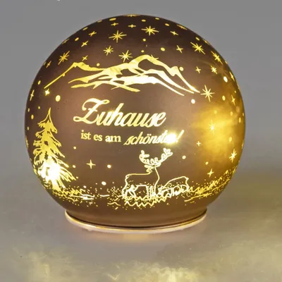 A decorative glass sphere with a Christmas-themed design, illuminated from within.
