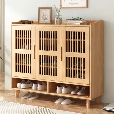 A wooden shoe cabinet with multiple compartments and doors, displaying shoes and slippers on its shelves and floor.
