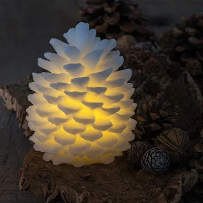 A lit pinecone decoration sits on a piece of bark, surrounded by other pinecones.