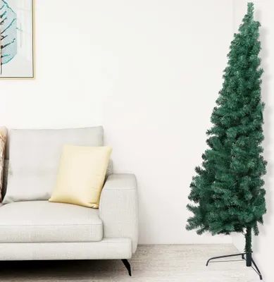 A slim artificial Christmas tree stands next to a sofa in a living room.