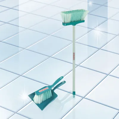 A broom and dustpan set on a tiled floor.