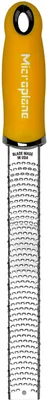A close-up, studio shot of a Microplane grater with a yellow handle.