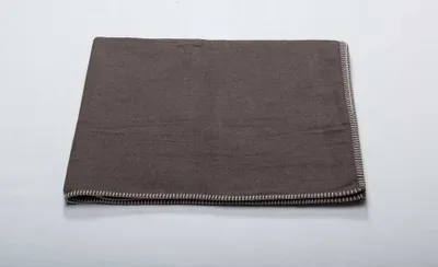 A folded brown blanket is shown on a light gray surface.