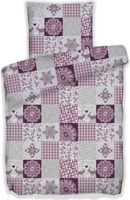 A folded duvet cover and pillowcase set with a patchwork design featuring winter motifs like snowflakes and deer.