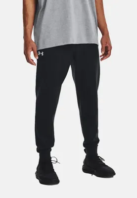 A person wearing black joggers and a grey t-shirt against a white background.
