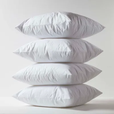 A stack of four white pillows against a plain white background.