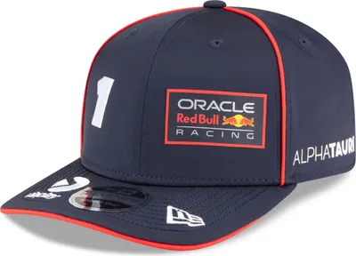 A close-up view of a navy blue baseball cap with red trim and various logos and text.