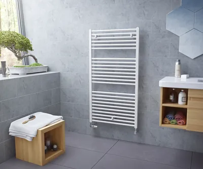 A modern bathroom with grey tiled walls and floor, featuring a white towel radiator, a wooden stool with towels, and a vanity unit with toiletries.