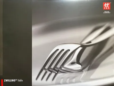 A close-up shot of several forks on a white plate, with a dark gray area on the left side of the image.