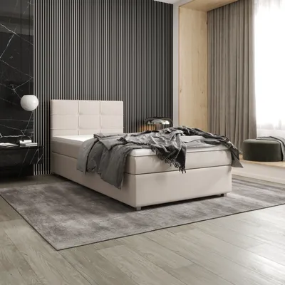 A bedroom scene featuring a beige boxspring bed with a grey blanket and pillows, set against a dark slatted wall and a light wood alcove with curtains.