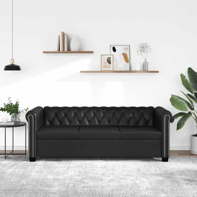 A black Chesterfield sofa is shown in a well-lit room with minimalist decor.