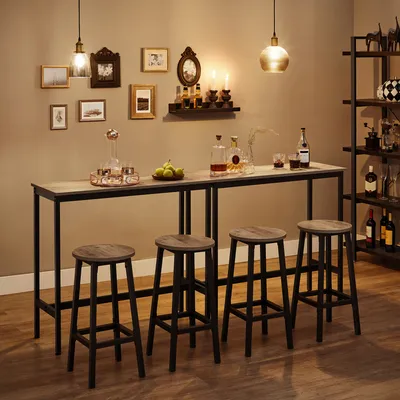 A bar area with a high table and four stools, decorated with framed pictures and bottles.
