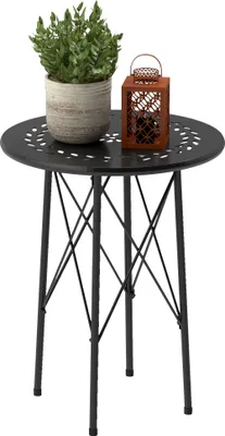 A small round black metal garden table with a potted green plant and a small brown lantern on top.