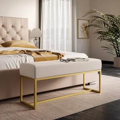 A bedroom scene with a bed, a bench, and a plant.
