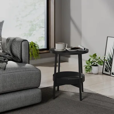 A black side table with a cup of coffee and a magazine on it, next to a gray sofa in a living room.