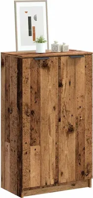 A wooden cabinet with two doors, decorated with a framed picture and two small decorative items on top.