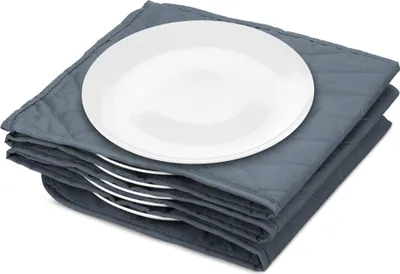A stack of white plates on a gray quilted mat.