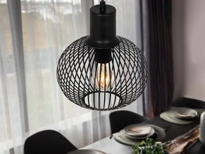 A black pendant light hangs over a dining table set for a meal.