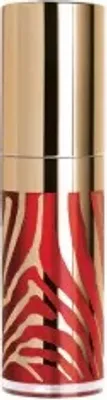 A close-up studio shot of a lipstick or gloss tube with a gold cap and a red and gold zebra-striped body.