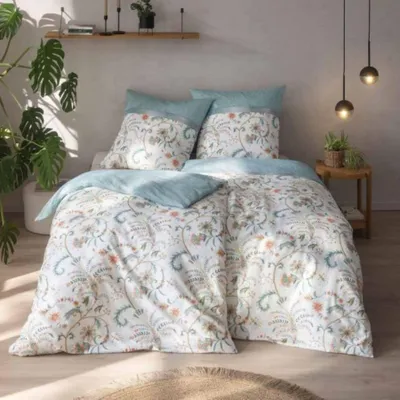 A bedroom scene with a neatly made bed featuring a floral patterned duvet and pillows.