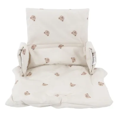 A cream-colored seat cushion for a high chair with a cartoon bear pattern.