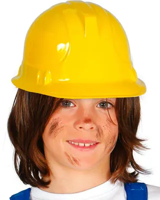 A child wearing a yellow hard hat and blue overalls, with dirt smudges on their face.
