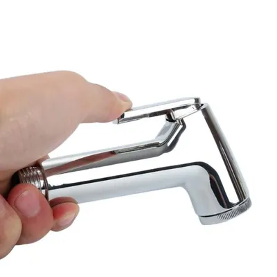 A hand holding a chrome-plated bidet sprayer.
