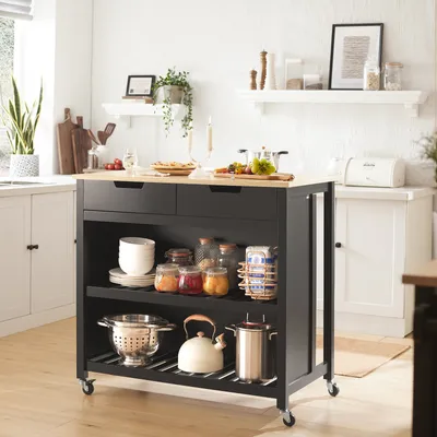 A kitchen scene with a black and wood kitchen island cart filled with various kitchen items.