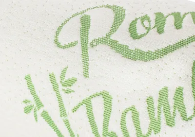 A close-up of a textured white fabric with green embroidered text and a floral design.